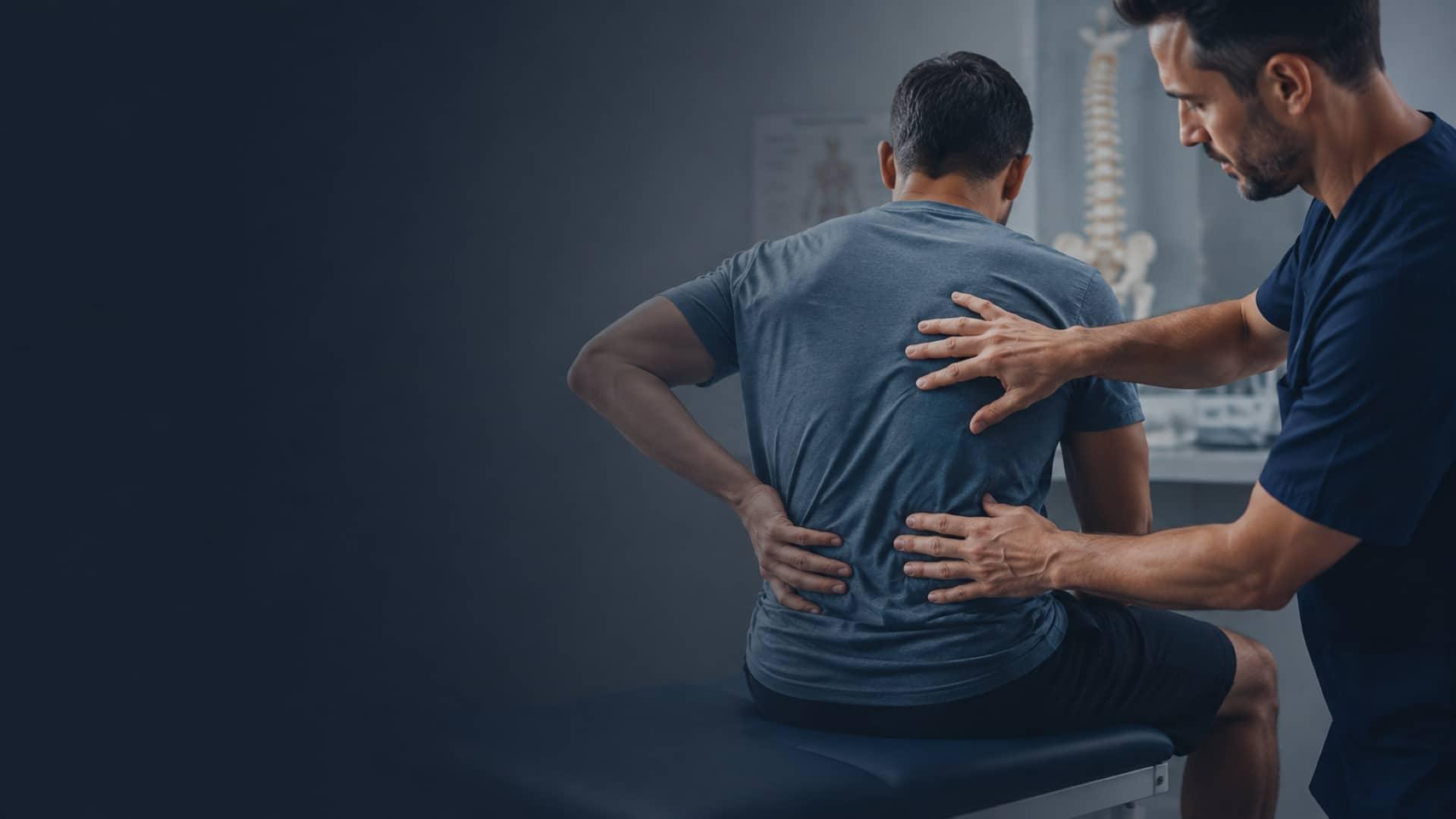 A pain management clinician examining a patient's lower back in a treatment room